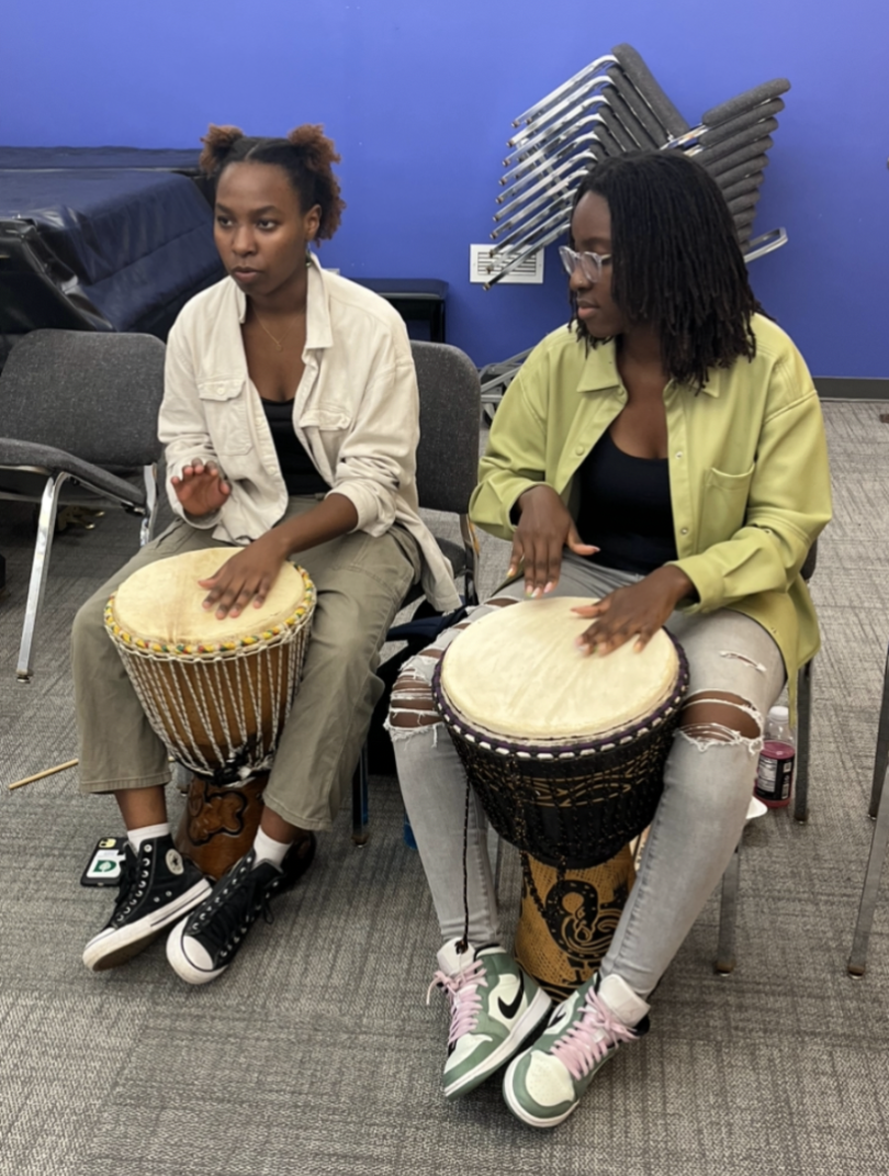 A picture of my friend and I sitting with djembe drums in between our feet as we played the Son rhythm.