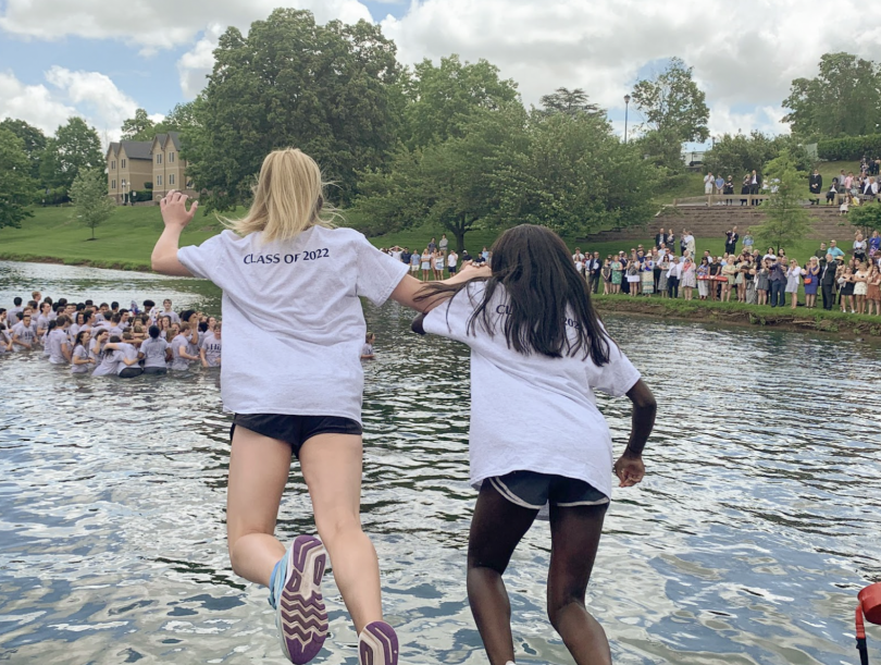 A picture of two girls jumping into a pond to celebrate a high school graduation tradition