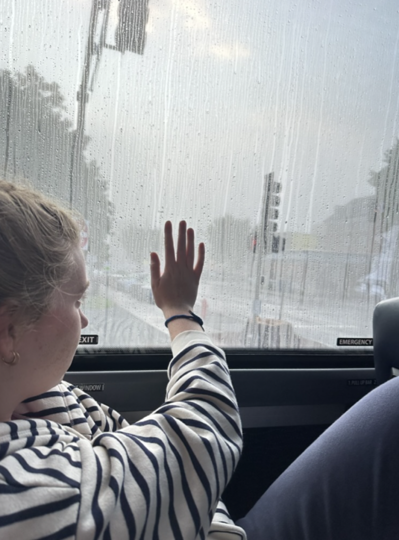 Girl holding her hand against a coach bus window
