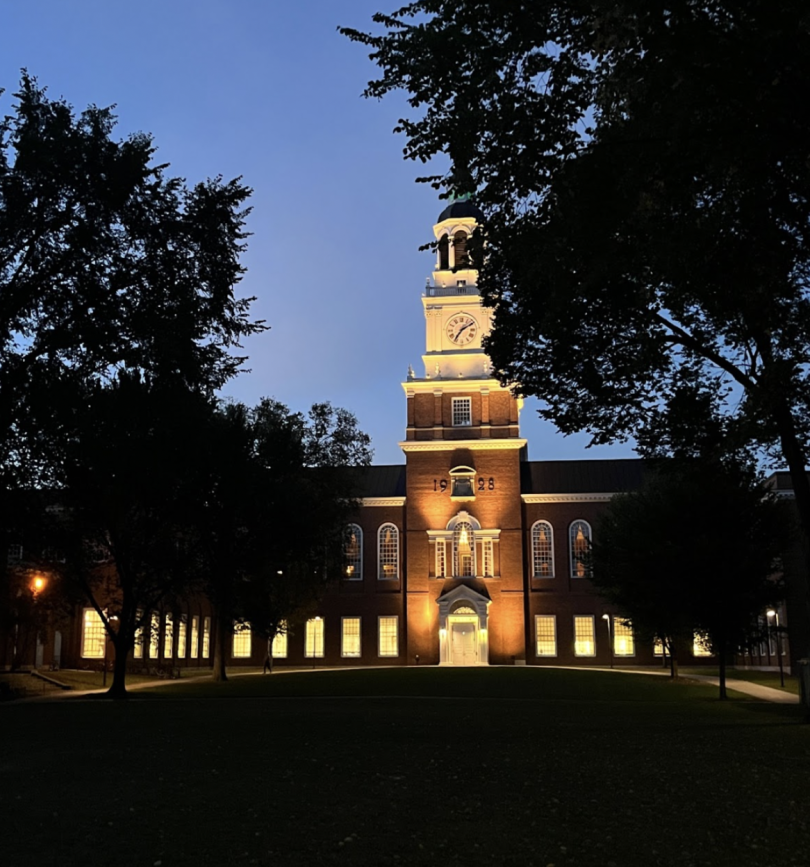A brick building with a tall church spire lit up at night. 