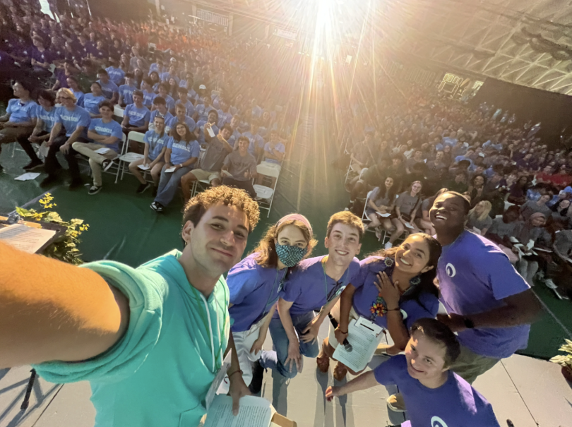 A selfie with the Class of 2028, wearing their housing merchandise, taken by Senior Orientation Leaders in purple shirts and teal hoodies.