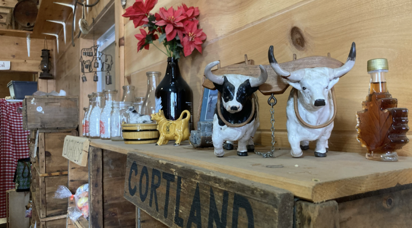 A view of the decorations inside the store, cow figurines, milk jugs, and a vase of flowers on top of a shelf
