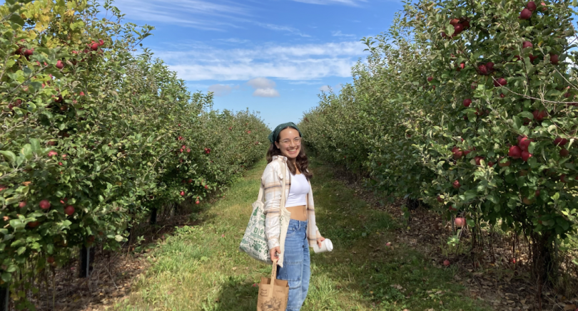Dezstany (another Peoples Places Pines blogger) poses in the middle of two rows of apple trees
