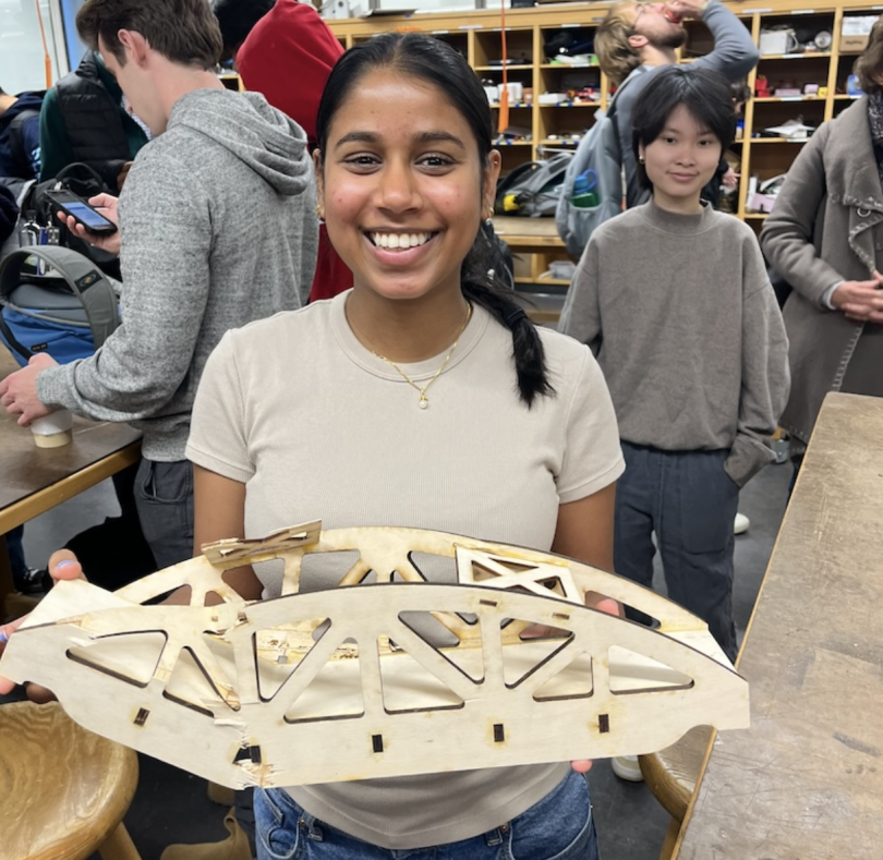 An image of a student holding a bridge that is broken at one end near the canopy.