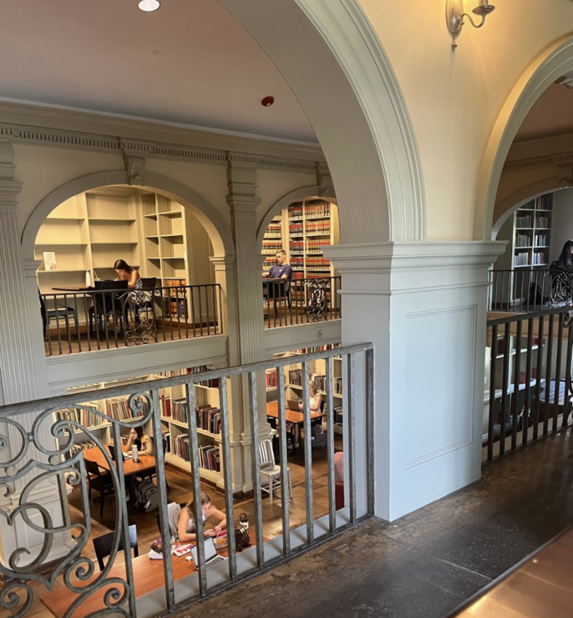 An indoor balcony looking over a library where students are sitting at desks and working.