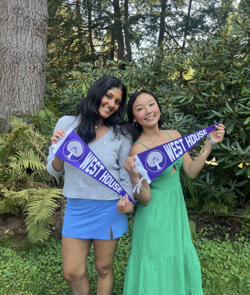 Madison and her roommate holding "West House" pennants, posing and smiling at the camera.