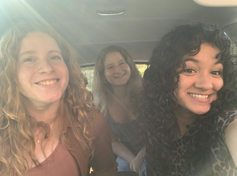 Three girls smiling in a car.