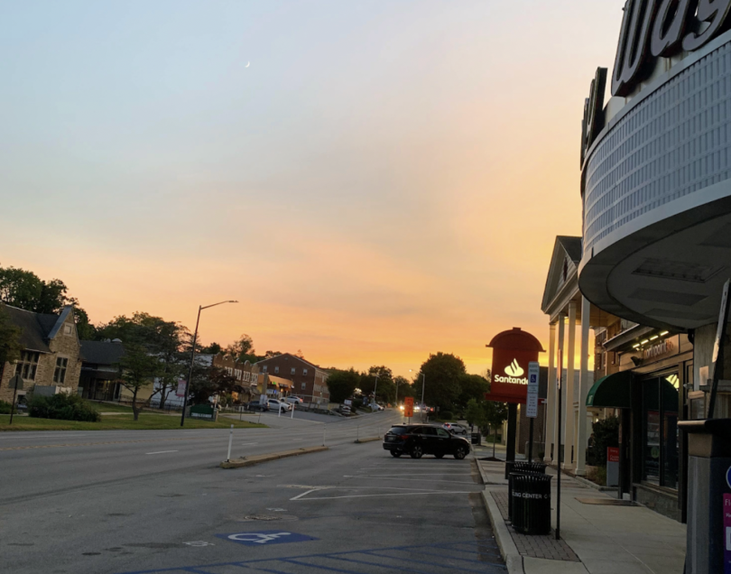 Picture of a street with buildings along it and a sunset in the sky.
