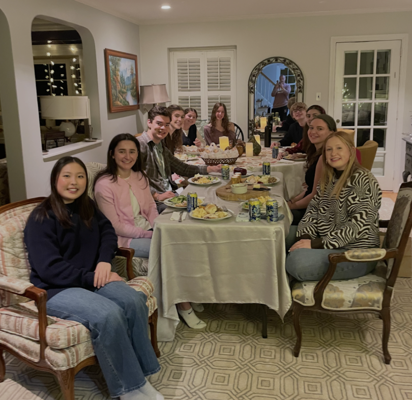 People sitting around a table with Thanksgiving food on it.