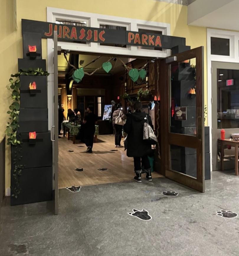 A doorway with the frame covered with dark gray boxes that read "Jurassic Parka" at the top in orange lettering.