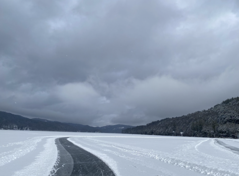 A wide angle view of a cleared path on the lake with mountains in the background.