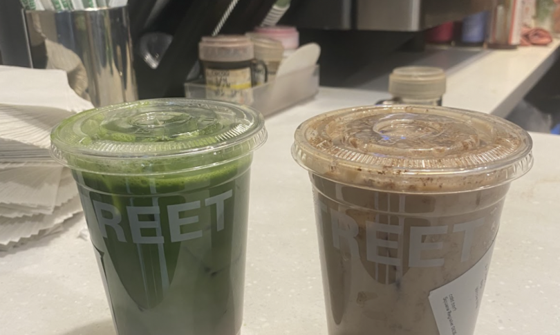 Two iced beverages in clear plastic cups with lids, placed on a countertop. One drink is a vibrant green matcha latte, while the other is a creamy, spiced chai latte. The cups have "STREET" printed on them.