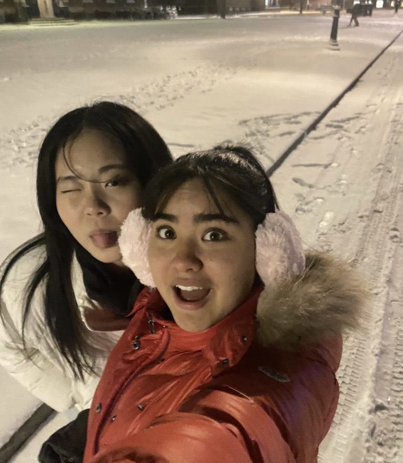 Two young women take a selfie in a snowy setting at night.