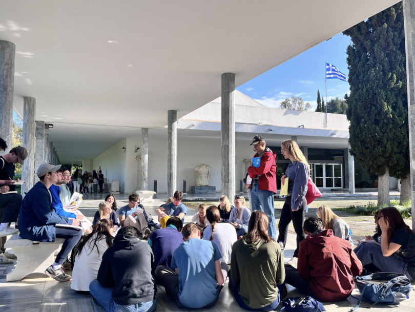 A class gathers around two professors