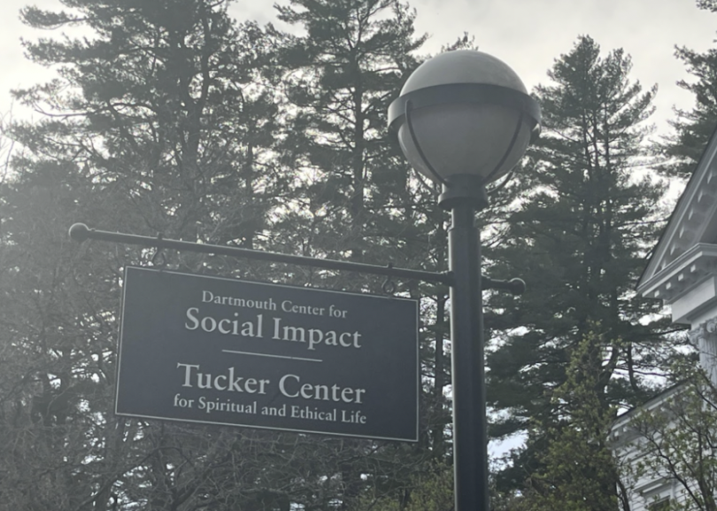 A lamppost with a sign attached that reads "Dartmouth Center for Social Impact," "Tucker Center for Spiritual and Ethical Life."