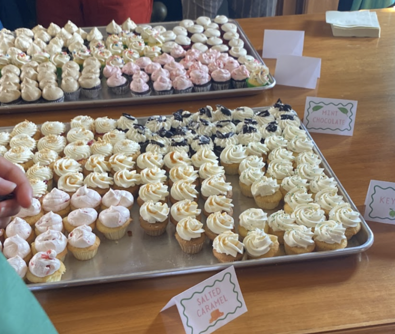 Trays of assorted mini cupcakes with different frosting flavors labeled as Salted Caramel, Mint Chocolate, and Key Lime on a wooden table.