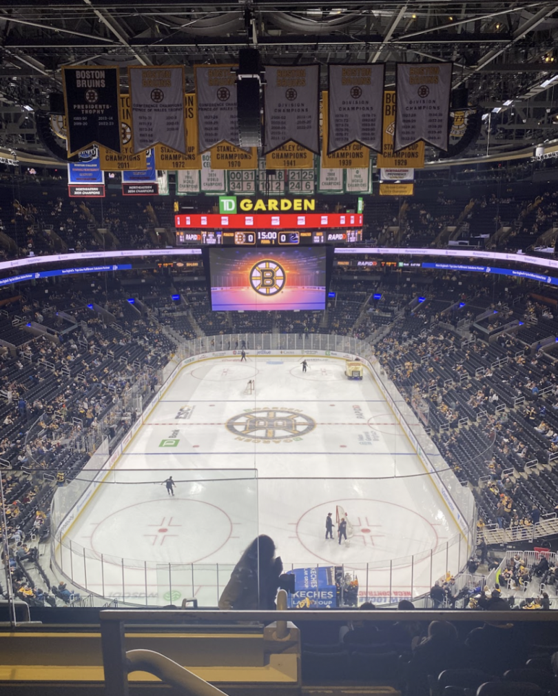 A wide view of TD Garden with fans filling the stands and the Boston Bruins logo displayed at center ice before the start of an NHL game.