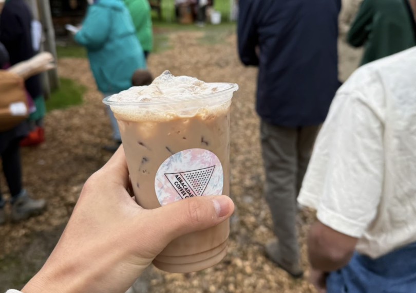 A cup of coffee with milk and ice cubes peeking at the top.