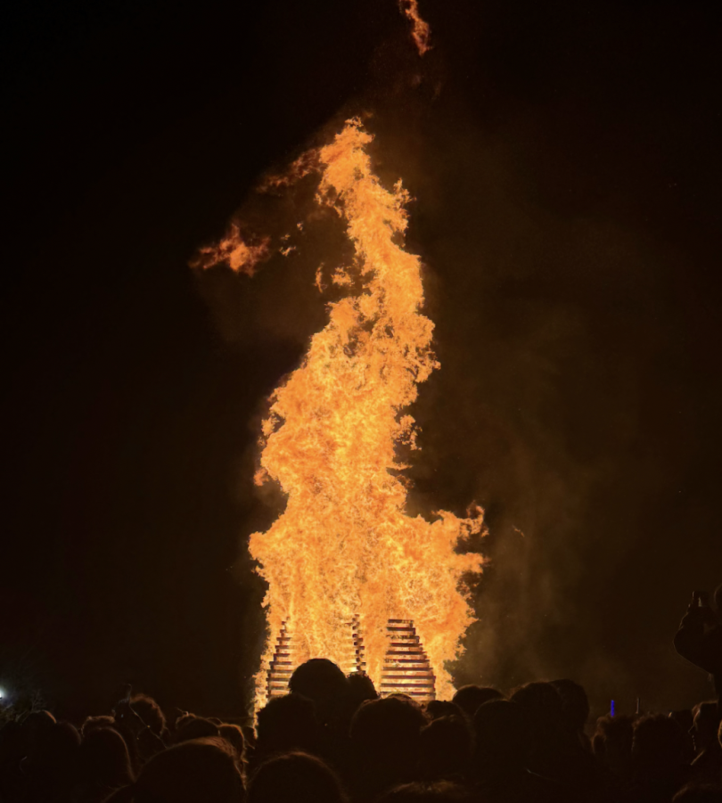 Giant campfire blazing in the dark around a huge crowd of Dartmouth students
