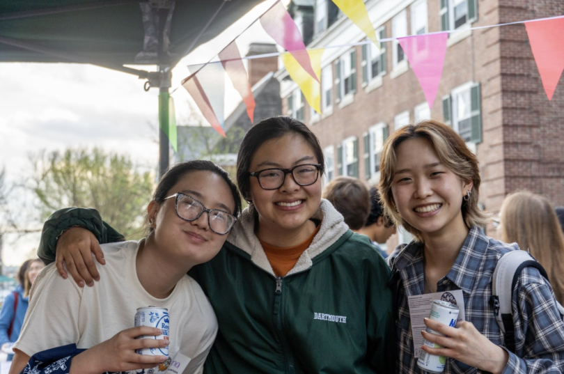 Three students at the night market smiling. Two of them are holding canned drinks.