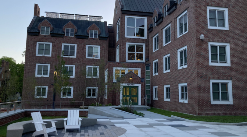 The front entrance of Andres Hall. The building is a mirror image of Zimmerman Hall, however, the entrance is on a flat side of the building. The building is red brick, decorated with large square windows with white trim. To the lower left of the image ar