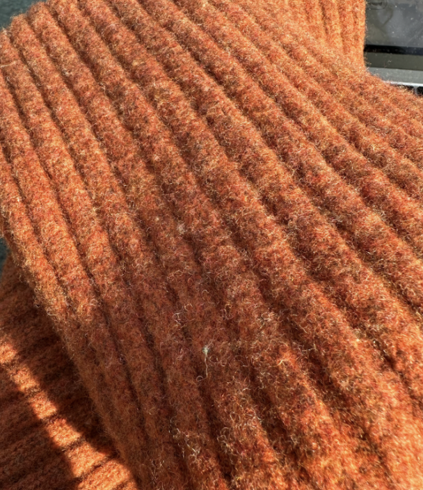 An image of an orange, fuzzy scarf folded in half.