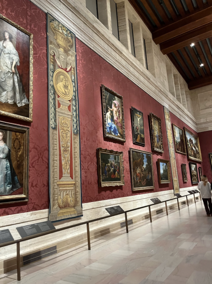 On the left is a red wall with ornate pictures lining the wall.