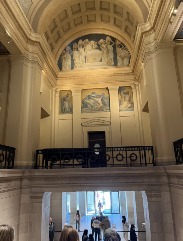A balcony with a black railing stands over marble walls and floors.