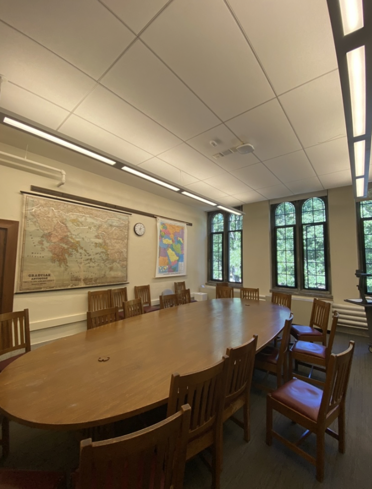 A photo of the classroom of my French class. A long wooden oval table and maps decorating the walls make the room seem very classical.