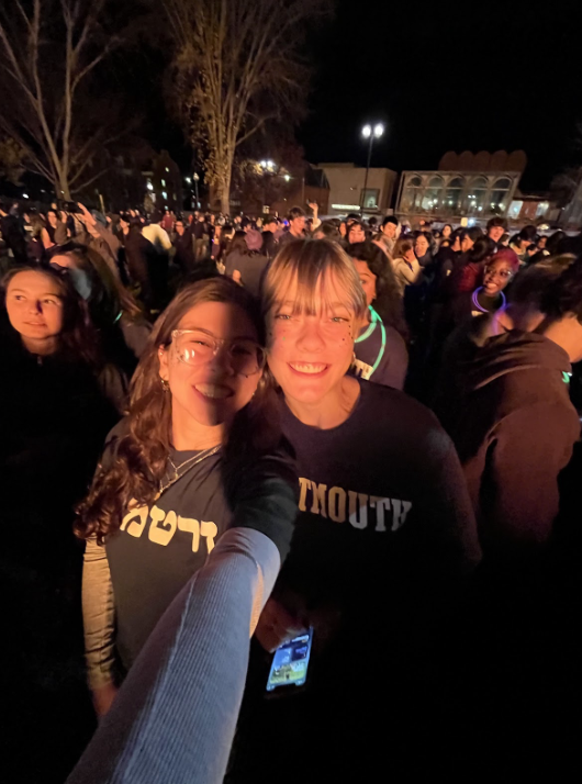 Serena and her friend Grace take a point five selfie. The glow of the fire is reflected in their faces and the crowd of people behind them.