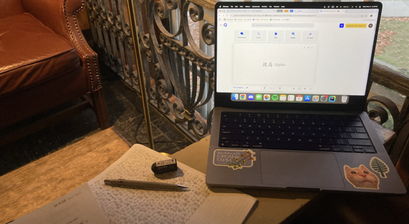 A view of my studying session at Sanborn Library. The Chinese characters 提高, meaning "to improve", are displayed on a laptop screen, to the laptop's left, a pencil and eraser sit on a notebook covered in writing.