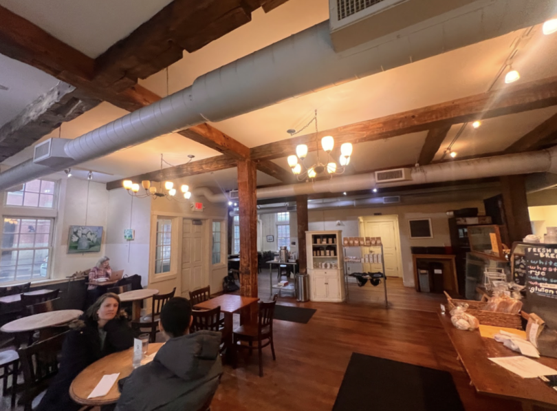 Interior of the cafe with wooden floors, tables and chairs.