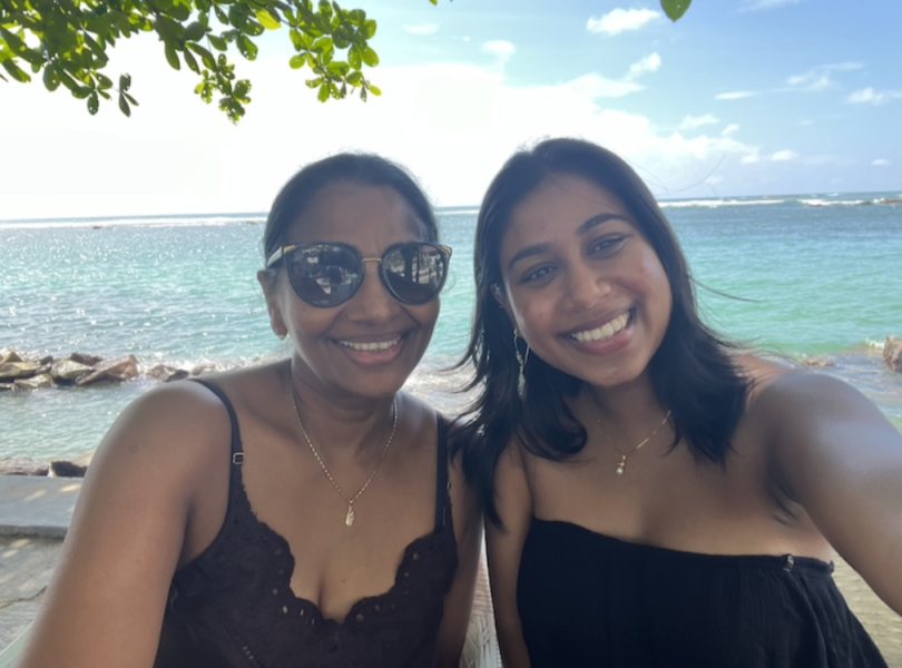 An image of two people smiling at the camera in front of a blue-green ocean.