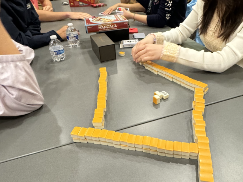 A group of students playing Mahjong at a table.
