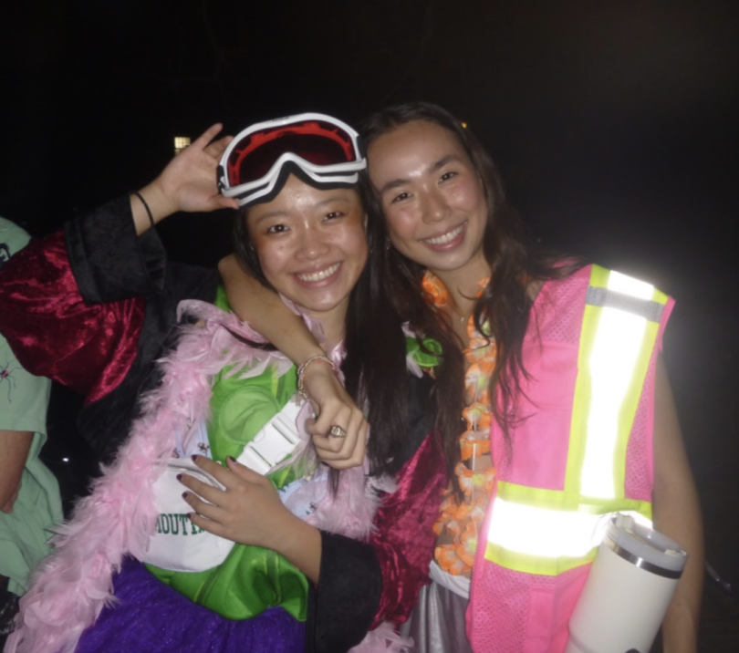 An image of me, Crystal, with a friend taken during the night. We are wearing an interesting combination of clothing, including ski goggles, a crossing guard vest, and a feather boa.