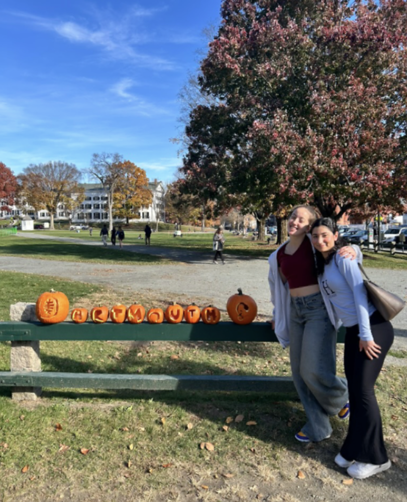 a line of pumpkins that reads Dartmouth, two girls smiling