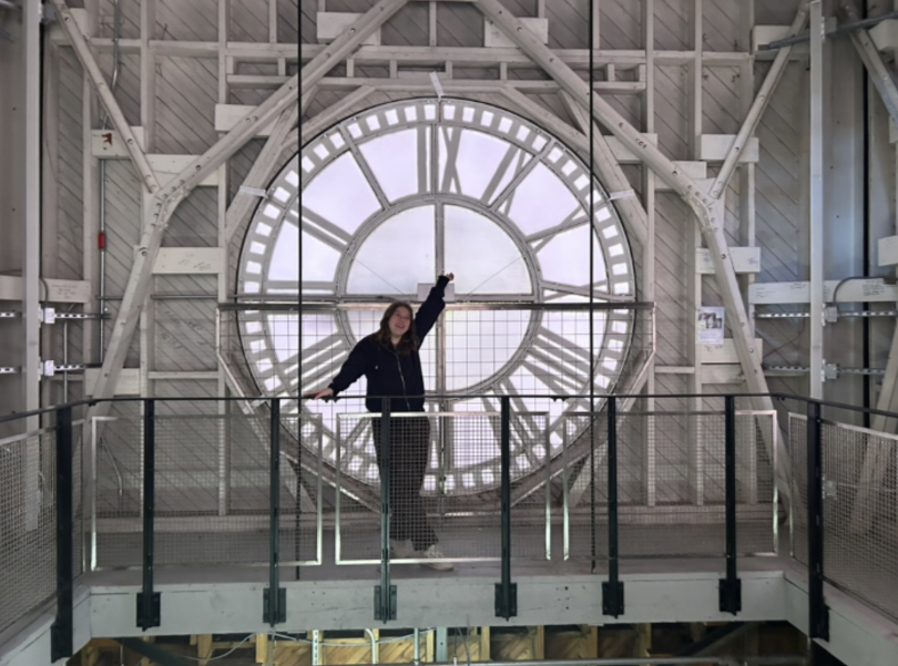 a person standing in front of a large clock
