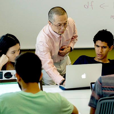 A photo of a professor helping students in a data class