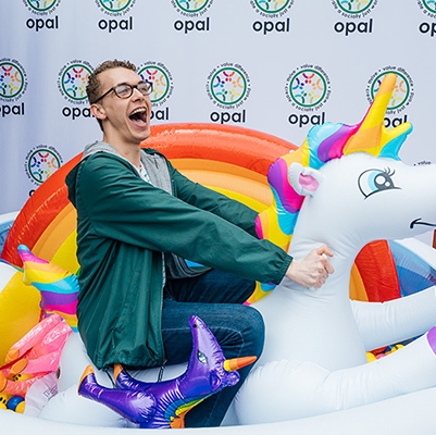 A photo of a student on an inflatable unicorn during a PRIDE event