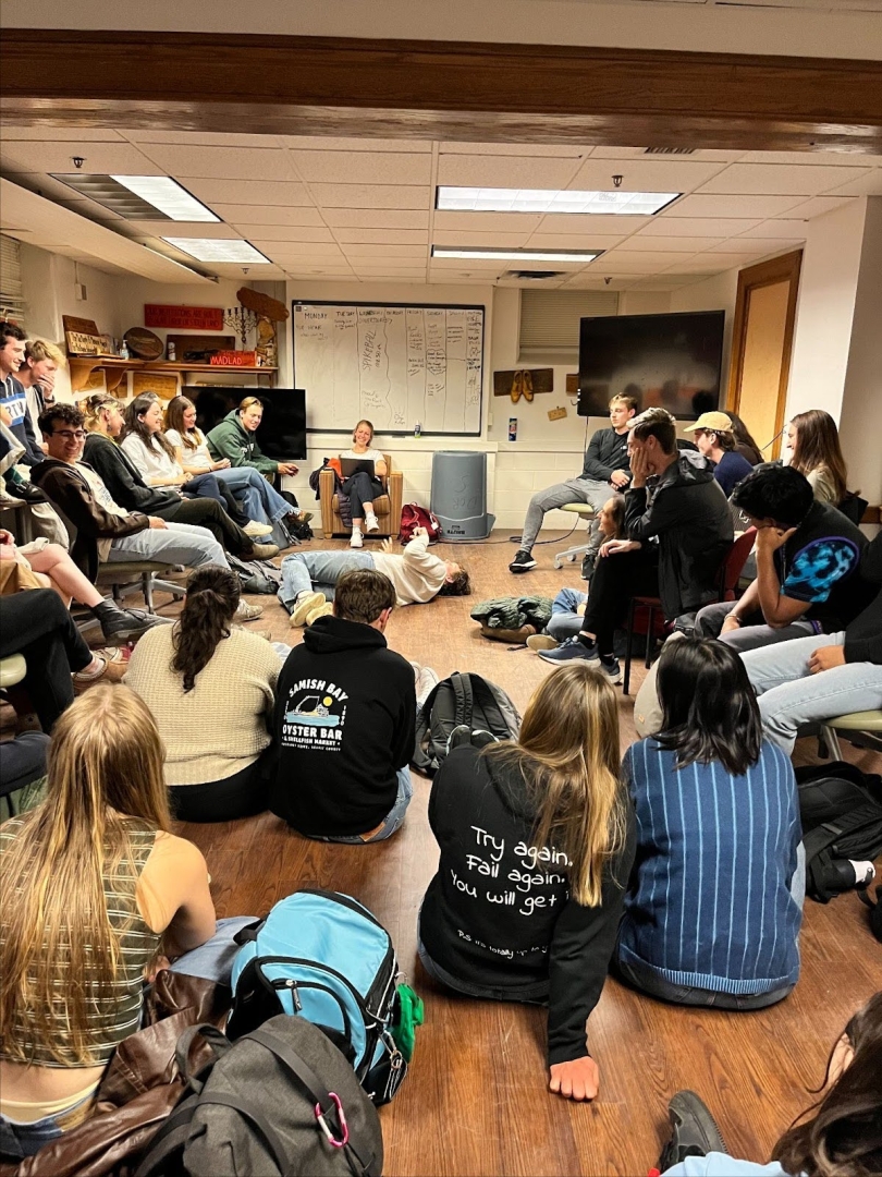 Many students sitting in a semi-circle on the floor during Ledyard Canoe Club Council