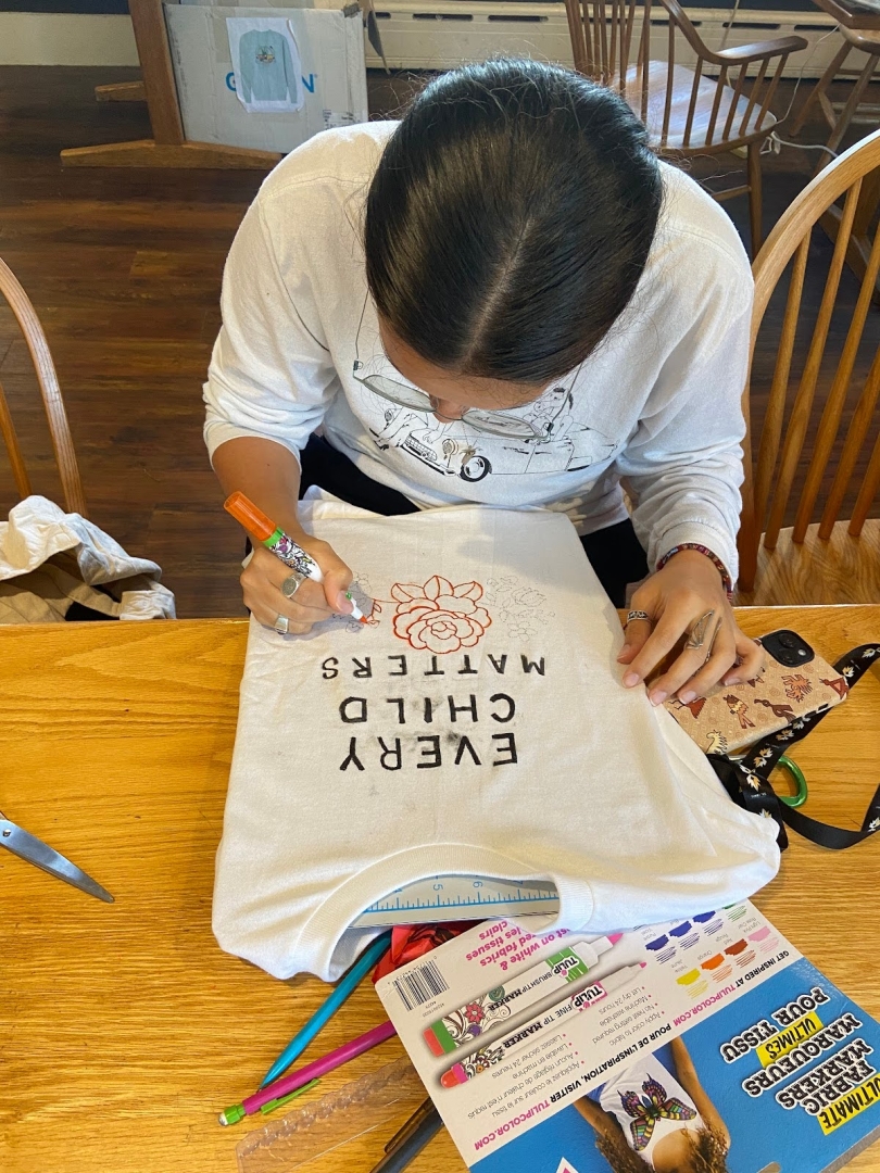A photo of my dear friend and fellow '28, Eloisa Roach making a beautiful shirt for Orange Shirt day!