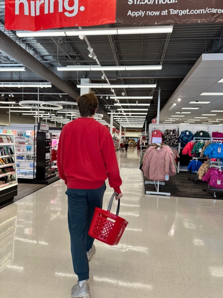 Noah holding a shopping basket and walking down an aisle at Target.
