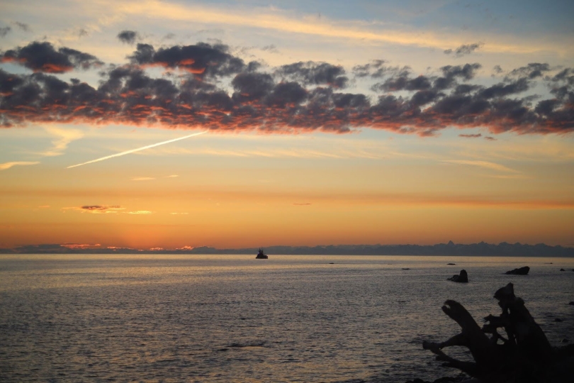 A picture of a sunset taken roughly at 11pm, it includes a fishing boat, mountains in the background, and a beautiful sunset.