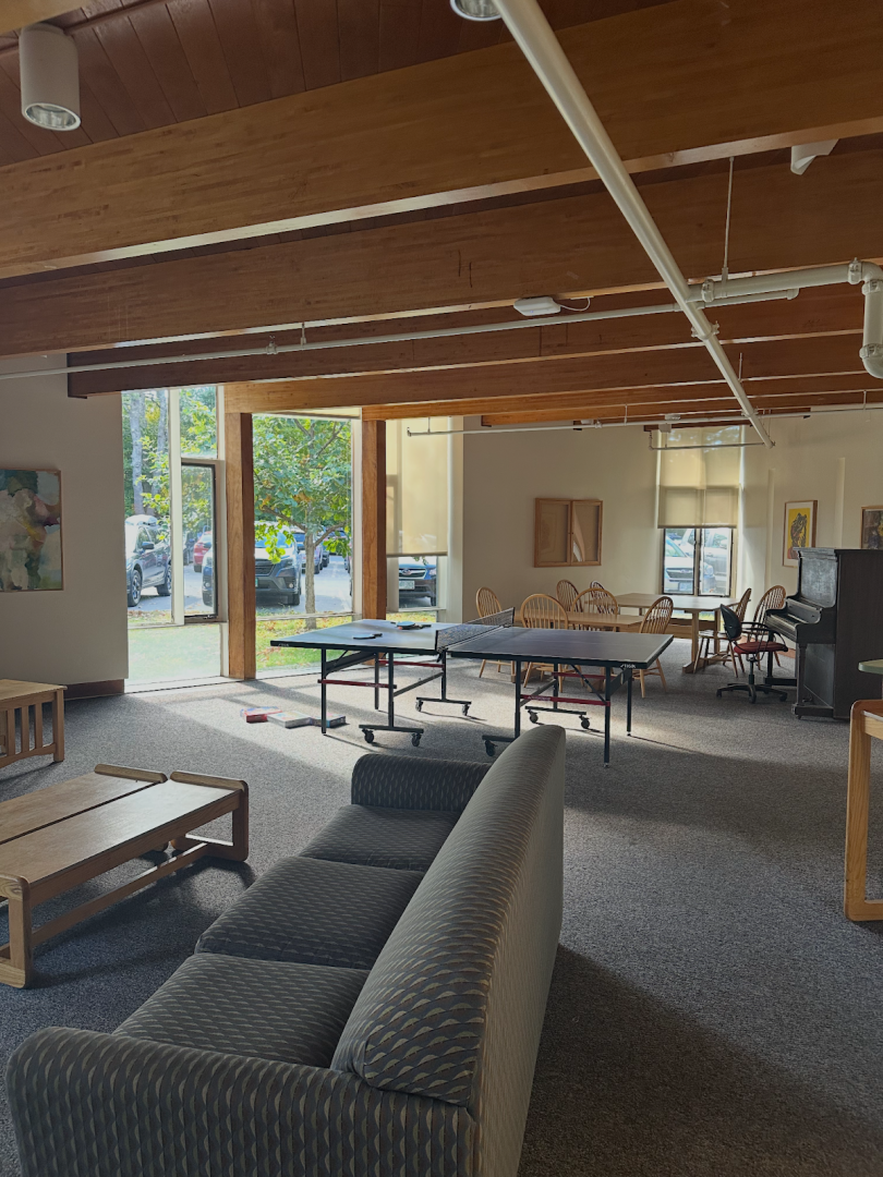 Big room with couch, chairs, piano, and ping pong table, and is also carpeted