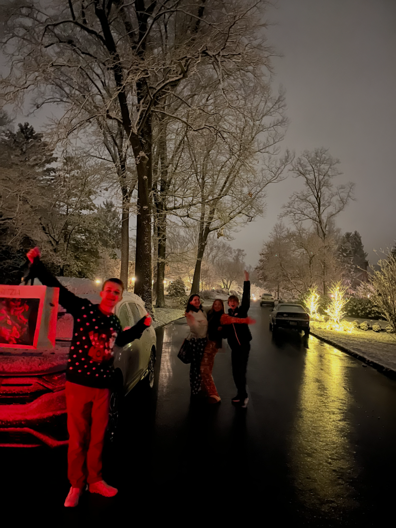 Four people standing in the road as it's snowing.