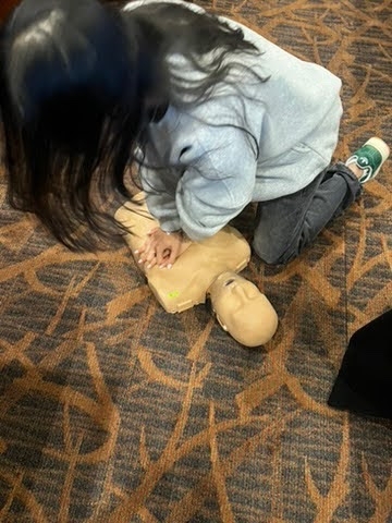 girl performing chest compressions on a dummy as part of the certification course