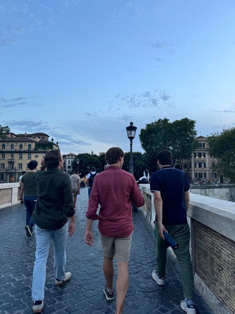  Tourists and locals walking across a pedestrian bridge in Rome in the early evening.