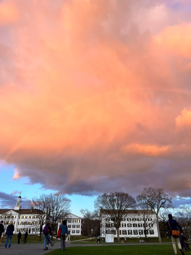 A large pink and orange cloud and faint rainbow over Dartmouth Hall and Reed Hall.