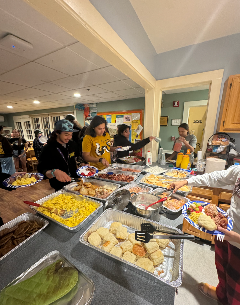 people stand gathered around a food buffett