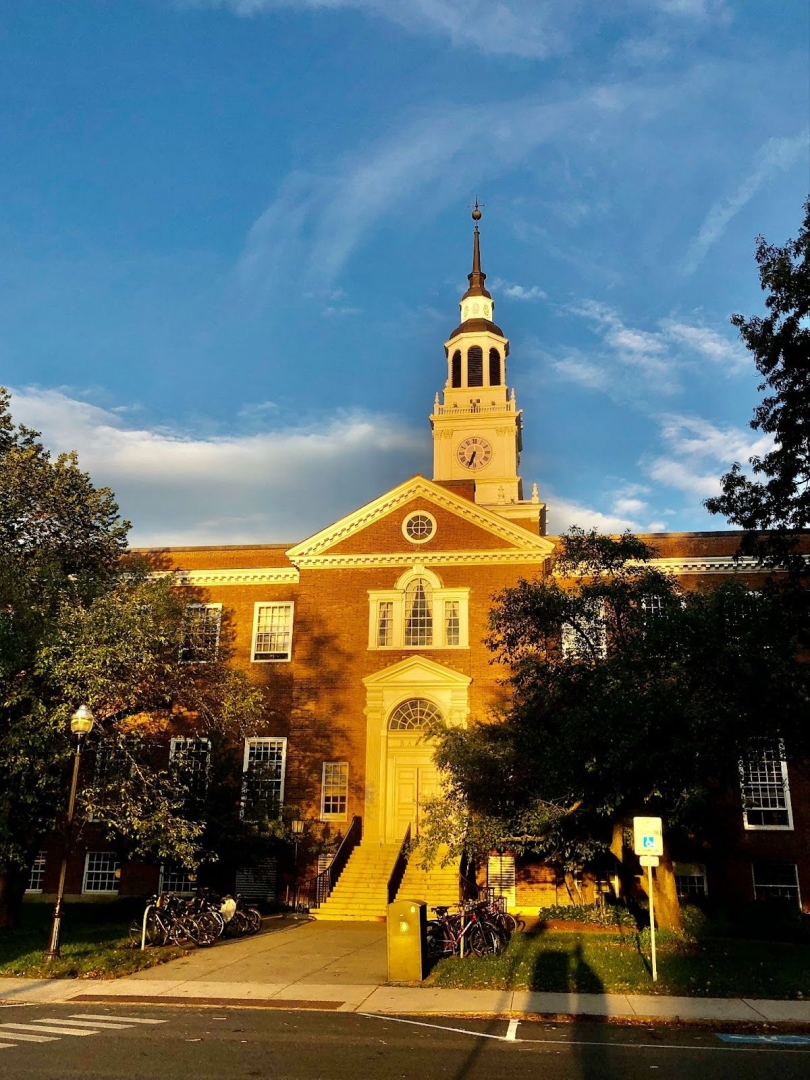 The colonial brick facade of Baker-Berry library lit with warm rays from a sunset. 